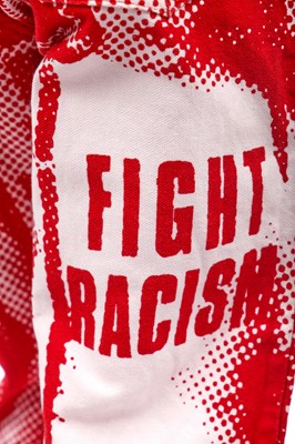 Lot 191 - A pair of Jean Paul Gaultier jeans printed with 'fight racism' and peace symbols, 2000s